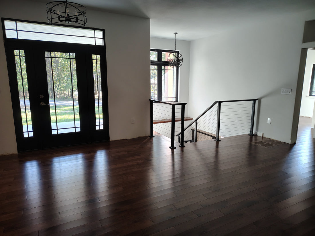 Black cable stair railing in a bright entryway with wood floors
