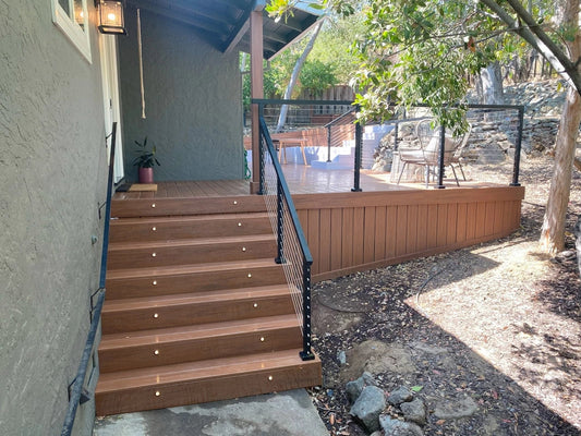 Modern stainless steel cable railing with black posts on an outdoor deck