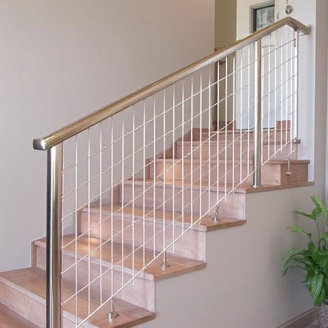 Stainless steel cable railing along an indoor wooden staircase