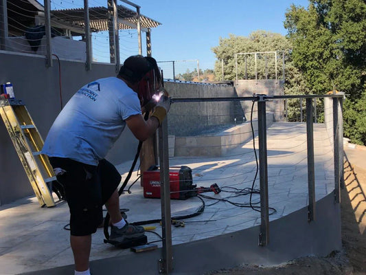 Worker installing metal cable railing posts on an outdoor terrace