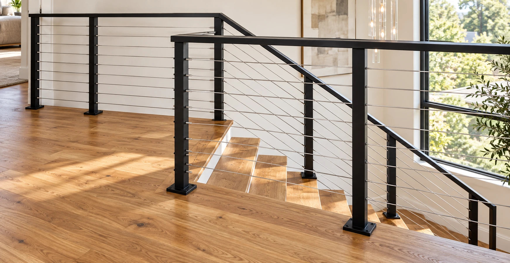 Black-post cable railing with a black top rail on a natural oak stair and landing.